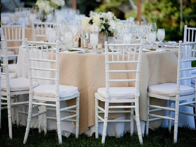 White Chiavari chairs with cushions set at a table with a burlap and lace runner for an outdoor wedding reception in Atlanta, Georgia