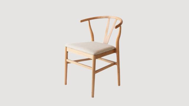 Natural wood wishbone dining chair with a cushioned seat, available to rent in Atlanta, Georgia